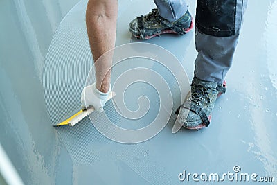 Construction worker renovates balcony floor and spreads watertight resin and glue Stock Photo
