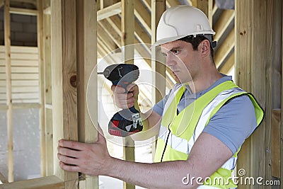 Construction Worker Using Cordless Drill On House Build Stock Photo