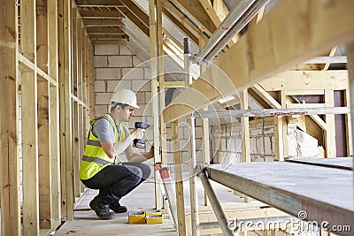 Construction Worker Using Drill On House Build Stock Photo