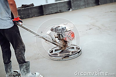 Construction worker using helicopter power tool and polishing sand and cement screed floor on the roof terrace of construction Stock Photo