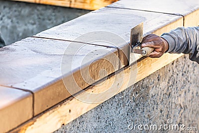 Construction Worker Using Stainless Steel Edger On Wet Cement Forming Coping Around New Pool Stock Photo