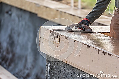 Construction Worker Using Wood Trowel On Wet Cement Forming Coping Around New Pool Stock Photo