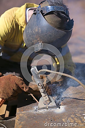 Construction worker welder wearing welding safety equipment glove helmet commencing welding hot work on industrial safety lifting Stock Photo