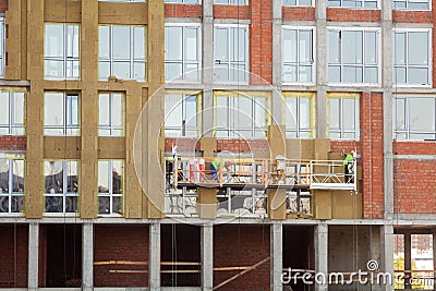 Construction workers insulating house facade. External wall insulation system or EWIS mineral wool for energy saving. Stock Photo