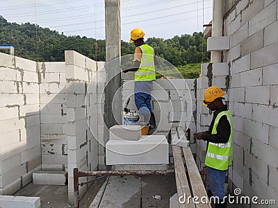 Construction workers laying autoclaved aerated concrete block at the construction site. Editorial Stock Photo