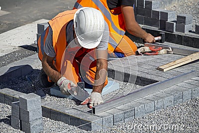 Construction workers laying paving bricks outdoor Stock Photo