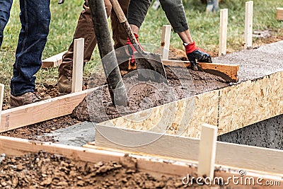 Construction Workers Pouring And Leveling Wet Cement Into Wood Framing Stock Photo