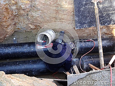 Construction workers risk their lives working inside deep trenches to install underground services pipe. Editorial Stock Photo