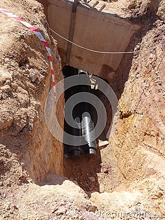 Construction workers risk their lives working inside deep trenches to install underground services pipe. Editorial Stock Photo