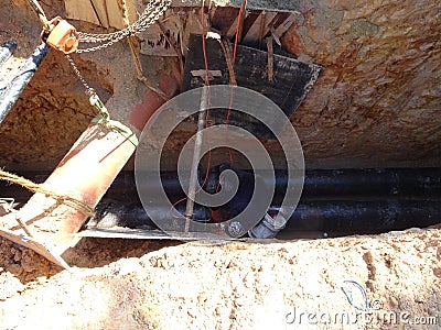 Construction workers risk their lives working inside deep trenches to install underground services pipe. Editorial Stock Photo