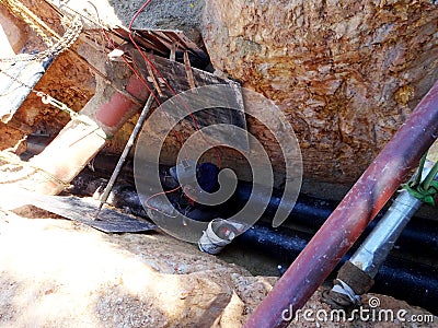 Construction workers risk their lives working inside deep trenches to install underground services pipe. Editorial Stock Photo