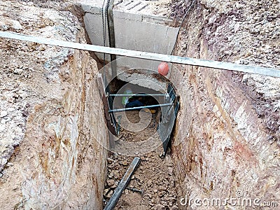 Construction workers risk their lives working inside deep trenches to install underground services pipe. Editorial Stock Photo