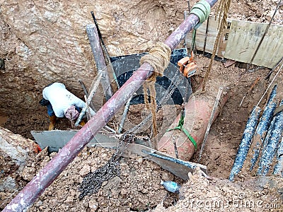 Construction workers risk their lives working inside deep trenches to install underground services pipe. Editorial Stock Photo