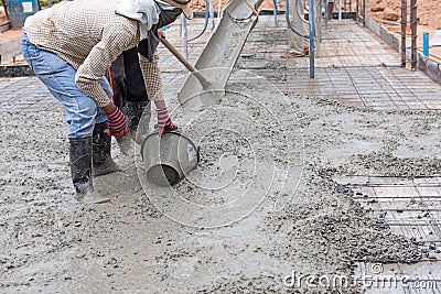 Construction workers spreading fresh poured concrete mix for house building Stock Photo