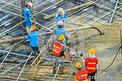 Construction workers using a concrete vibrator gasoline engine type at the construction site to compact the liquid concrete in r Editorial Stock Photo