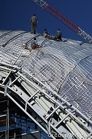 Construction workers working on the roof of a building tied with Stock Photo