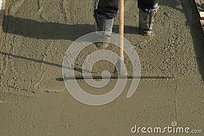 Builder mason worker leveling concrete with long trowel on construction site. Stock Photo