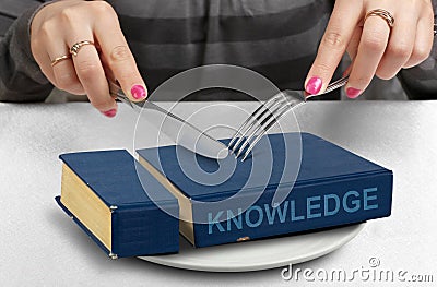 Consume knowledge concept, hands cut book on plate Stock Photo