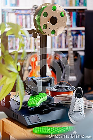 Consumer 3D-printer makes a bright green shoe sole in living room scene. Stock Photo