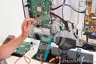 The consumer electronics repair engineer measures the voltage Stock Photo