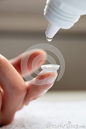 Contact lense cleaning on finger to correct nearsightedness and blurred vision eyesight by optician or oculist Stock Photo