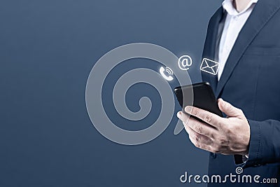 CONTACT US. businessman holding cell mobile phone with with mail, phone, email icon. cutomer support concept. blue background Stock Photo