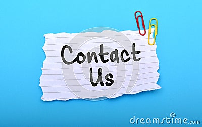Contact us hand written on paper with blue background Stock Photo