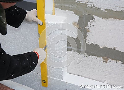 Contactor installing rigid styrofoam board insulation on house wall for energy saving. Stock Photo