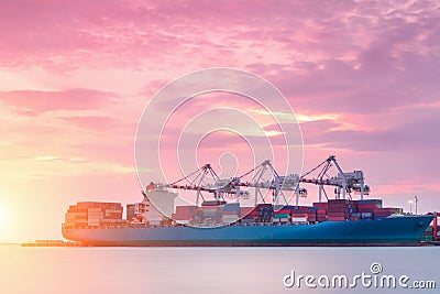 Container Cargo freight ship with working crane bridge in shipyard at dusk for Logistic Import Export Stock Photo