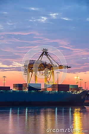 Container Cargo freight ship with working crane bridge in shipyard at sunrise Stock Photo
