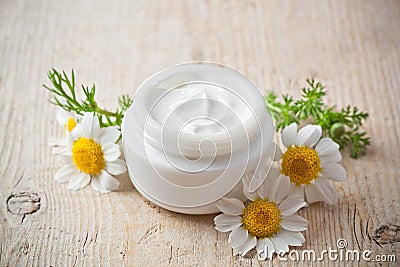 Container with cream and chamomiles Stock Photo