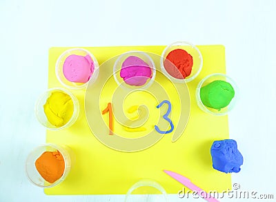 Containers with colorful plasticine and the child made numbers one , two, three. white wooden background Stock Photo