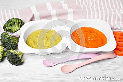 Containers with healthy baby food, spoons and ingredients on white wooden table Stock Photo