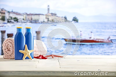 Containers for lotions and sunscreen oils on bright table, a towel, a starfish and in the distance the sea and clear sky. Stock Photo