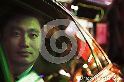 Contemplative Businessman in the back seat of a car looking out through window at night, Beijing Stock Photo