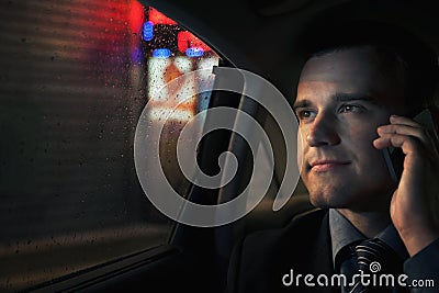 Contemplative Businessman on the phone in the back seat of a car looking out at night in Beijing Stock Photo