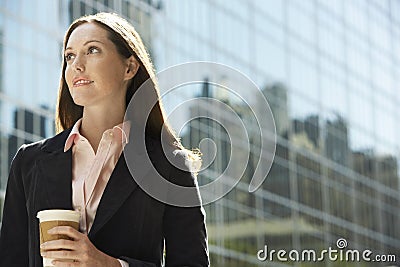 Contemplative Businesswoman With Drink Outside Building Stock Photo