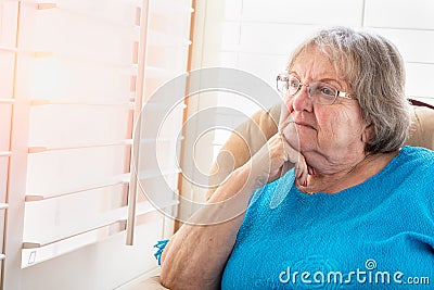 Contemplative Senior Woman Gazing Out of Her Window Stock Photo