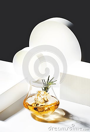 Contemporary still life with whiskey, scotch or bourbon glass with rosemary, shard ice on black white background with geometric Stock Photo