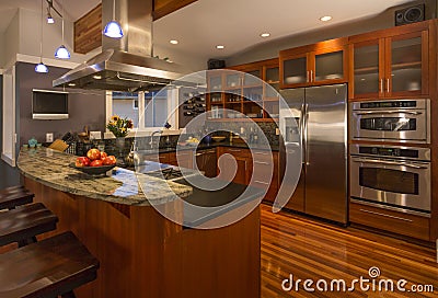 Contemporary upscale home kitchen interior with wood cabinets and floors, granite countertop and stainless steel appliances Stock Photo