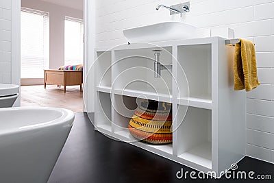 Contemporary white painted MDF bathroom unit, with colourful basket and black vinyl flooring Stock Photo