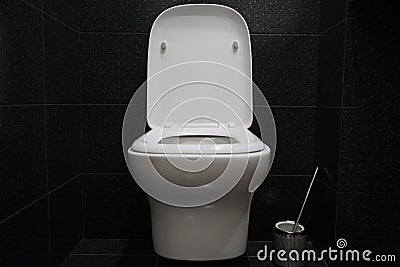 Contemporary white wall hung toilet. Black shiny tiles. Modern bathroom design. Cleanliness and hygiene Stock Photo