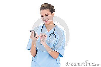 Content brown haired nurse in blue scrubs using a mobile phone Stock Photo