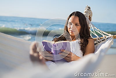 Content woman lying on hammock reading book Stock Photo