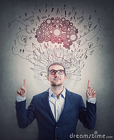 Contented businessman pointing up forefingers, looking satisfied. Cogwheel brain and sketches as thoughts over head. Confident Stock Photo