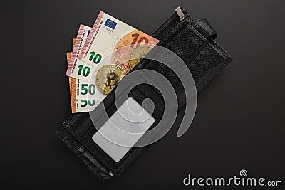 The contents of a man`s wallet - euro notes and bitcoins on a black background Stock Photo