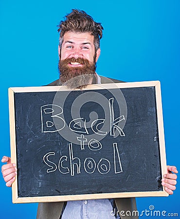 Continue your education with us. Teacher bearded man stands and holds blackboard with inscription back to school blue Stock Photo