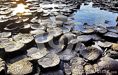 The continuous trickle of water over the hexagonal Basalt slabs of Giants Causeway Stock Photo