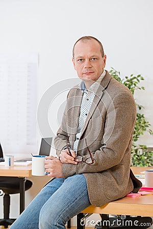 Contractor Holding Coffee Cup And Eyeglasses On Desk In Office Stock Photo