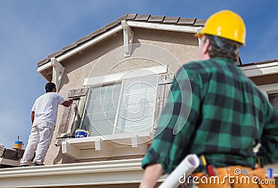 Contractor Overlooking Painter Painting House Stock Photo